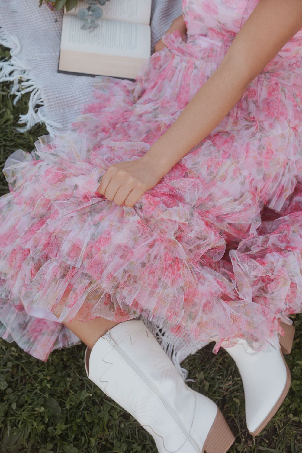 Pink tulle ruffle skirt paired with crisp white boots creates a feminine, playful outfit detail on grass.