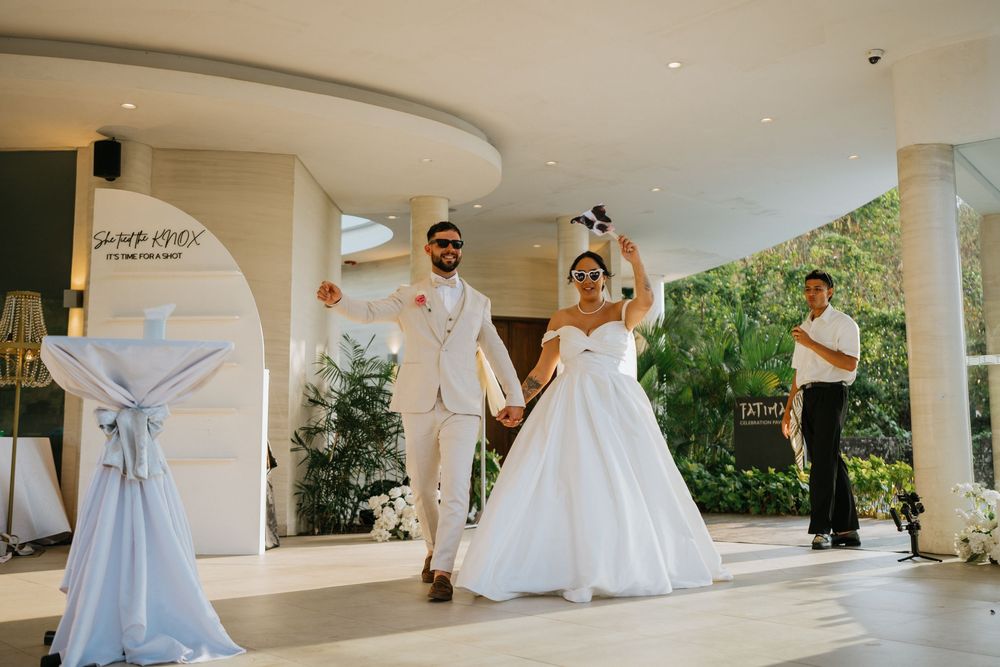 Wedding party poses under covered walkway in formal attire.