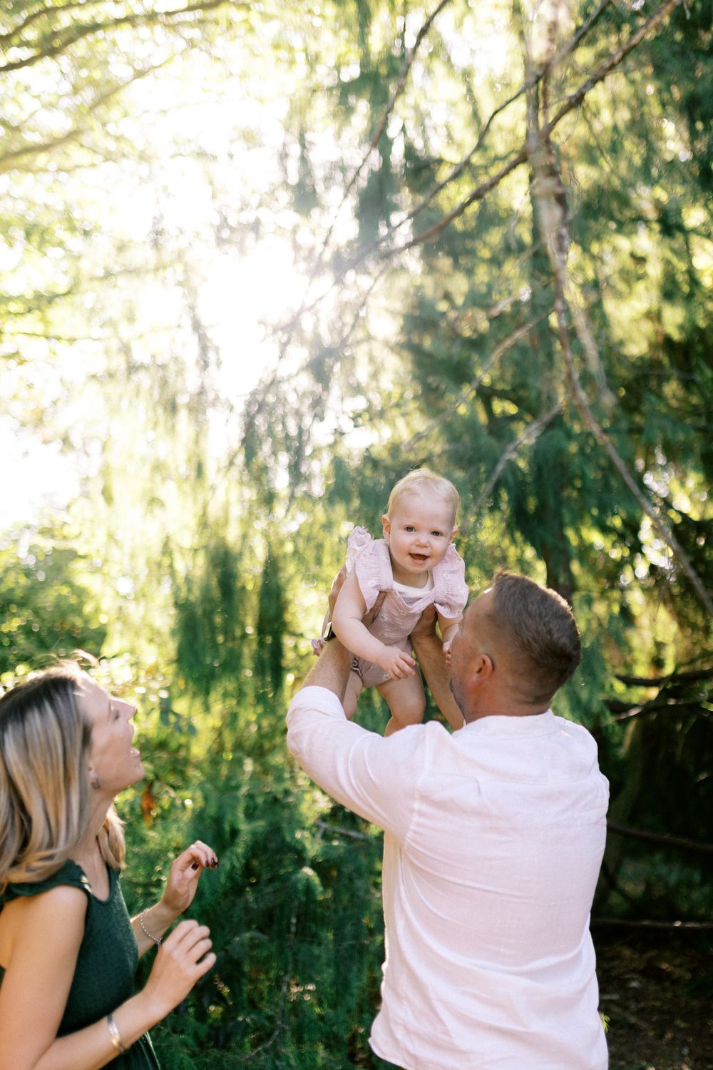 Joyful outdoor family photoshoot with playful moments in a green forest setting.
