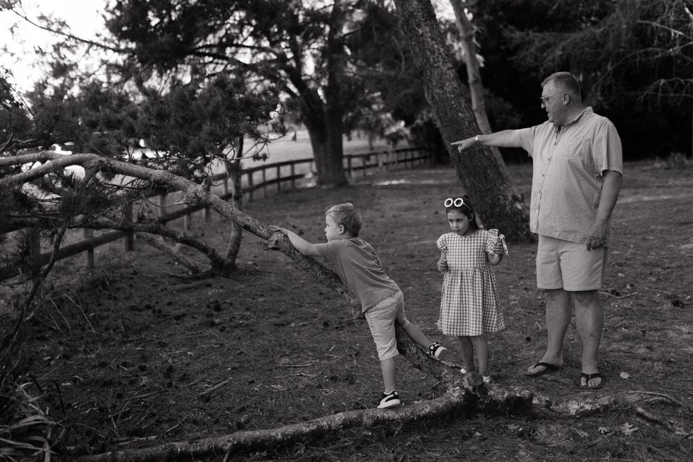 Black and white candid photos capture playful family moments in a natural outdoor setting.