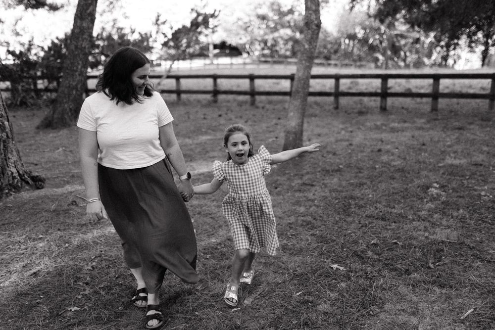 Two people enjoying a playful moment together in a grassy outdoor setting in black and white.