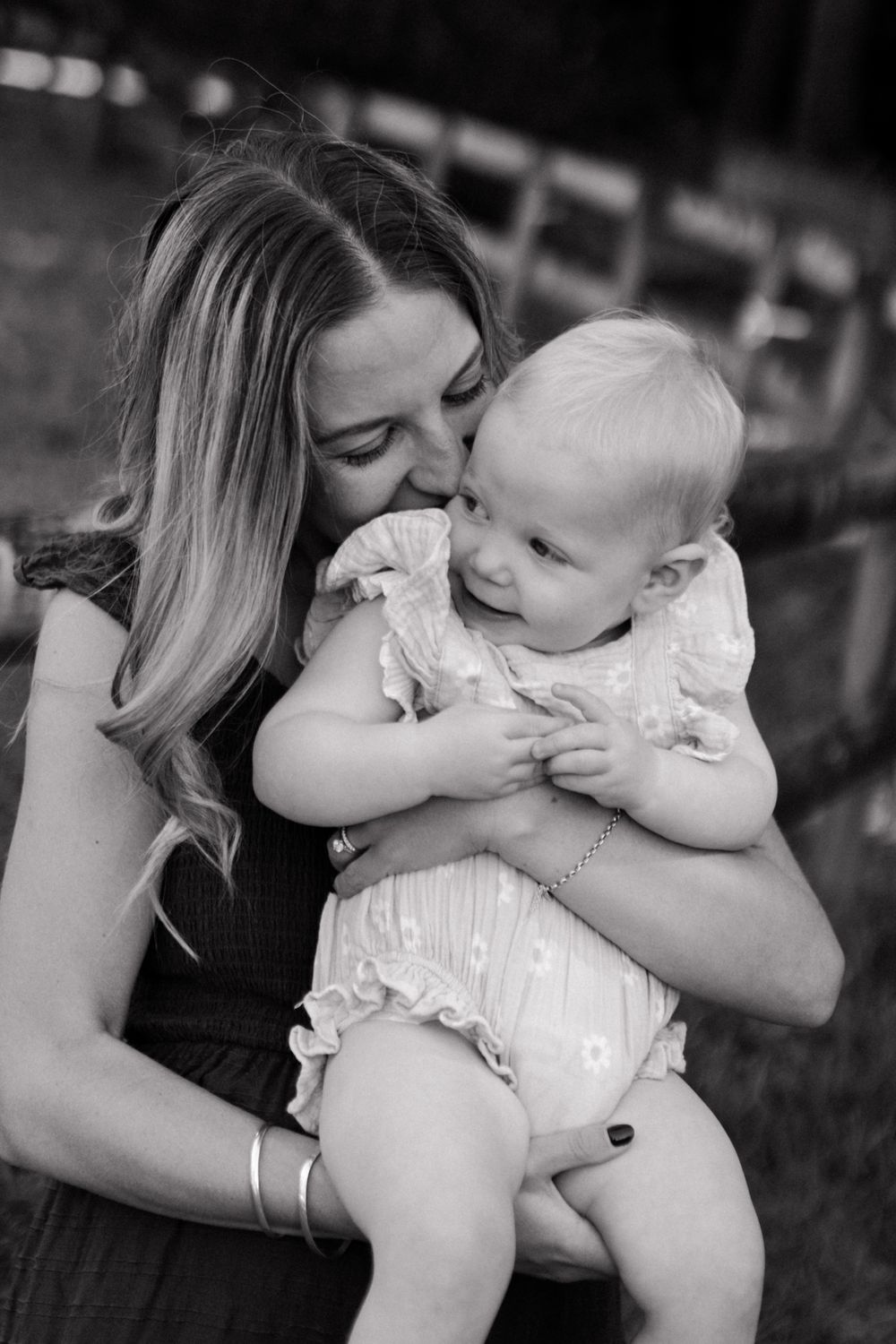 An intimate black and white moment showing affectionate interaction between parent and baby outdoors.