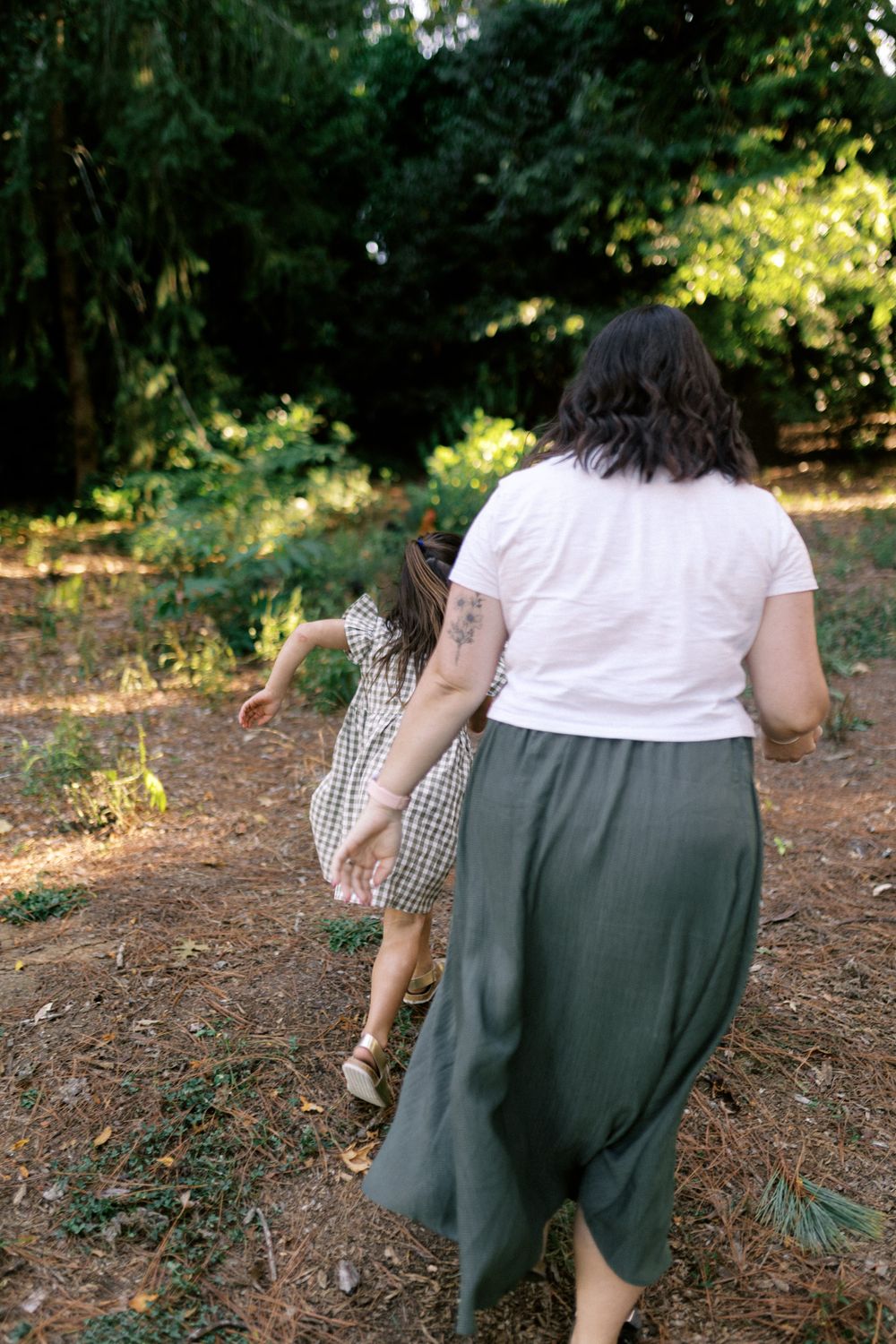 A candid sequence of figures walking through a sunlit forest path.