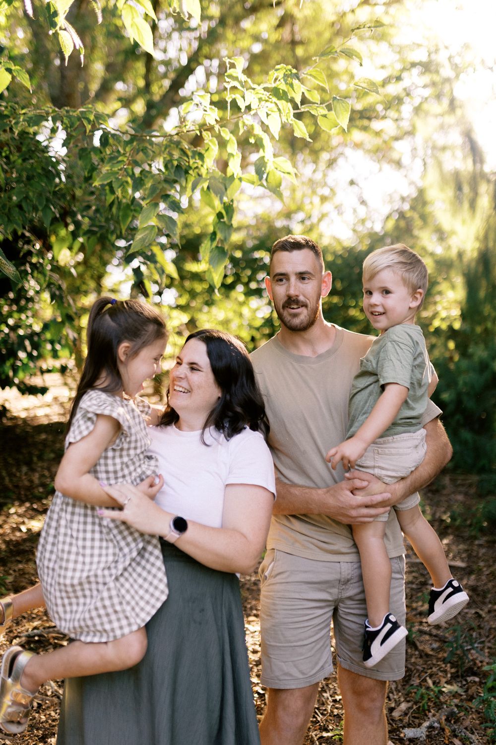 Family photo session in a lush green outdoor setting during golden hour.