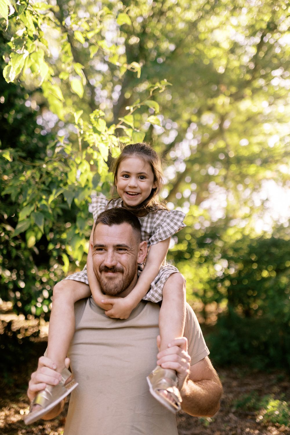 A joyful piggyback ride moment captured in a sun-dappled garden setting.