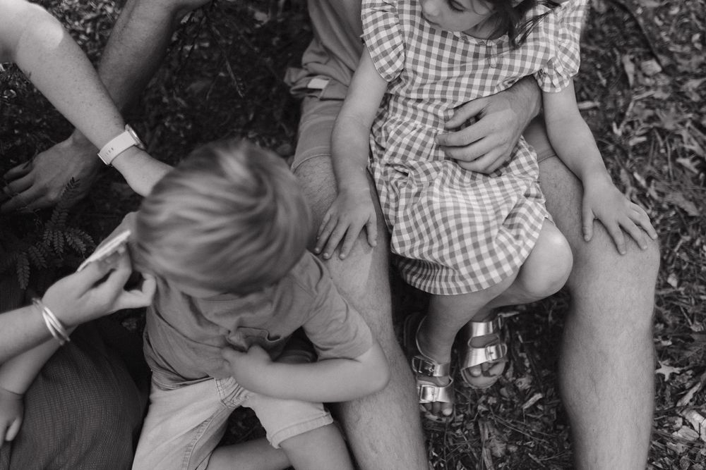 Series of intimate black and white photos showing tender family interactions on the ground.