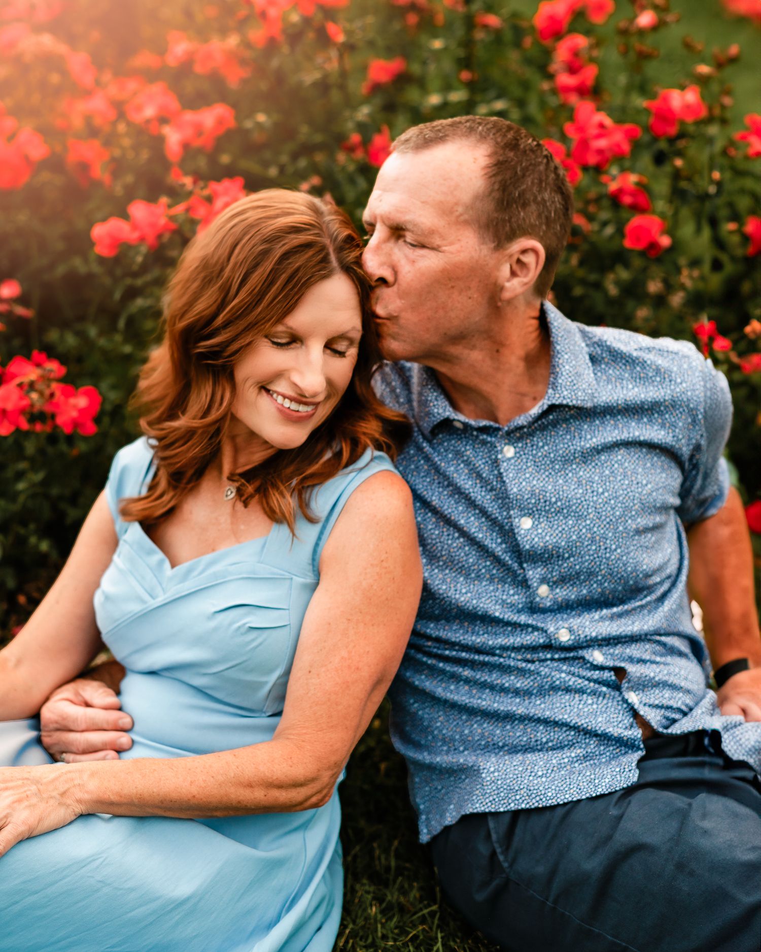 husband kissing his wife's temple in a flower field in Colorado