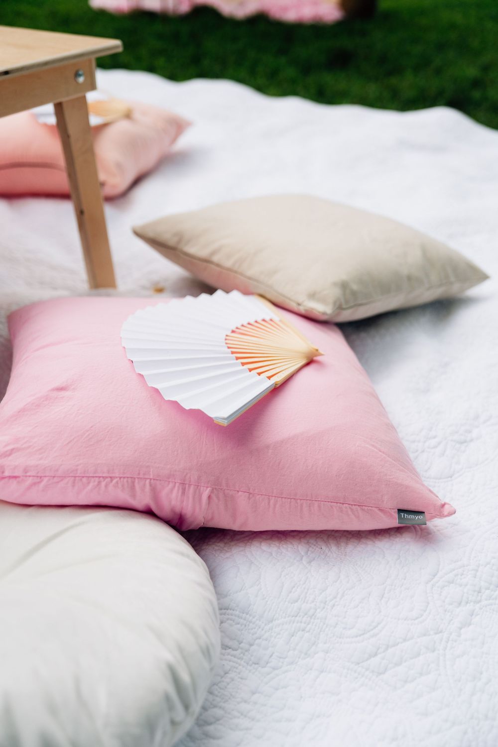 A collection of pink and white decorative pillows with a shell accent arranged in a gradient sequence on a white surface.