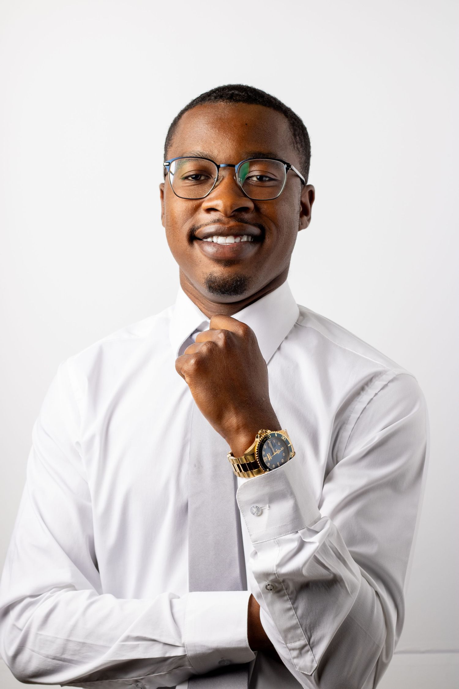Professional man in white dress shirt and tie smiles confidently in headshot photo.