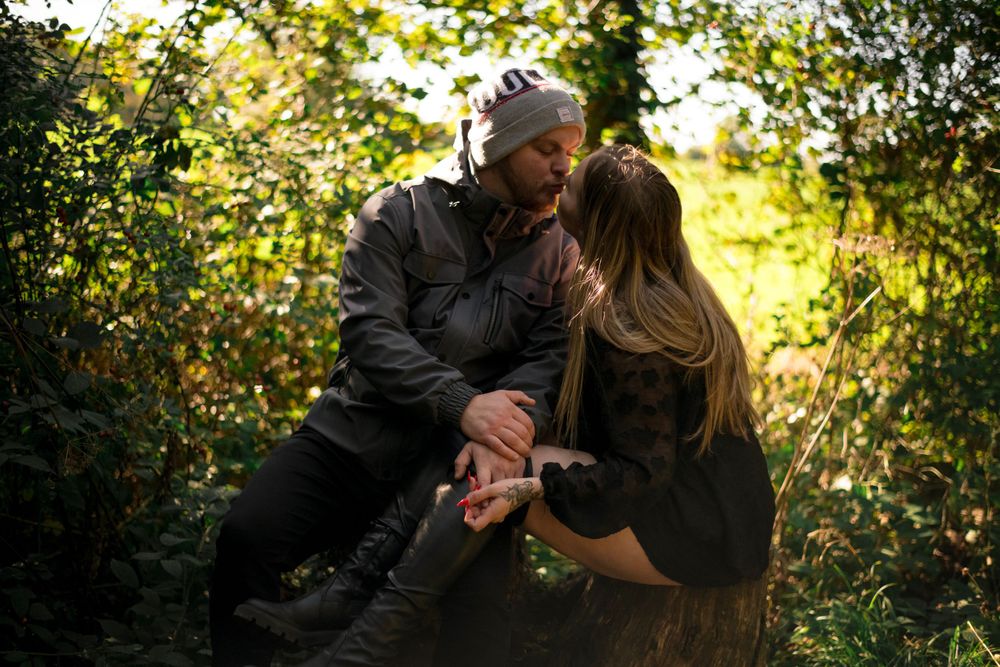 A romantic moment captured between a couple in a sunlit wooded setting.