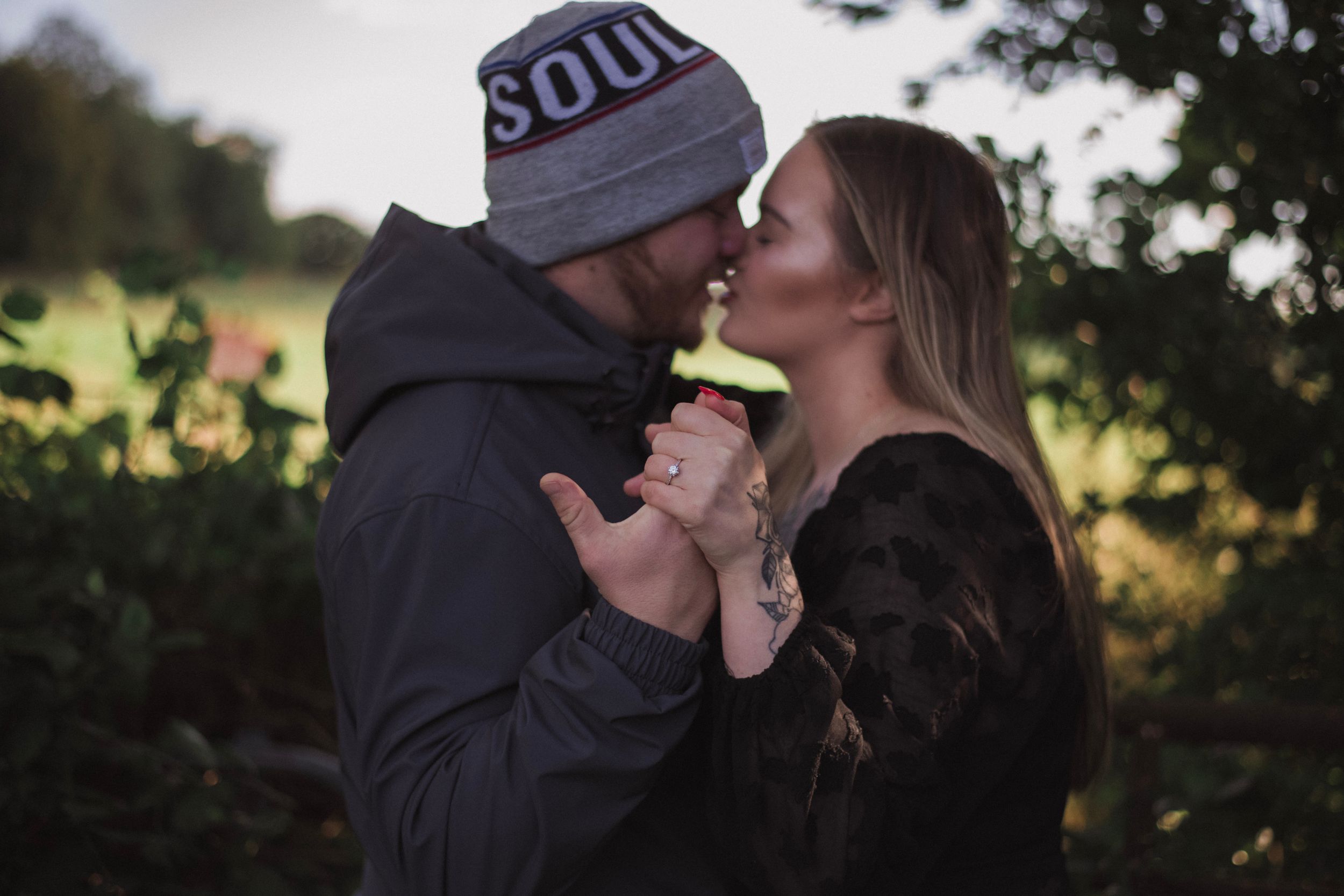 A tender moment between a couple illuminated by golden hour lighting in a natural setting.