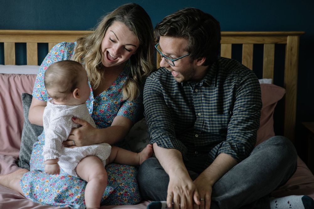 A joyful family scene on a bed with parents and baby sharing laughs together.