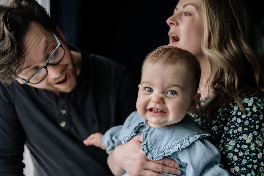 Candid family moment with a baby in blue dress being held by caregivers.