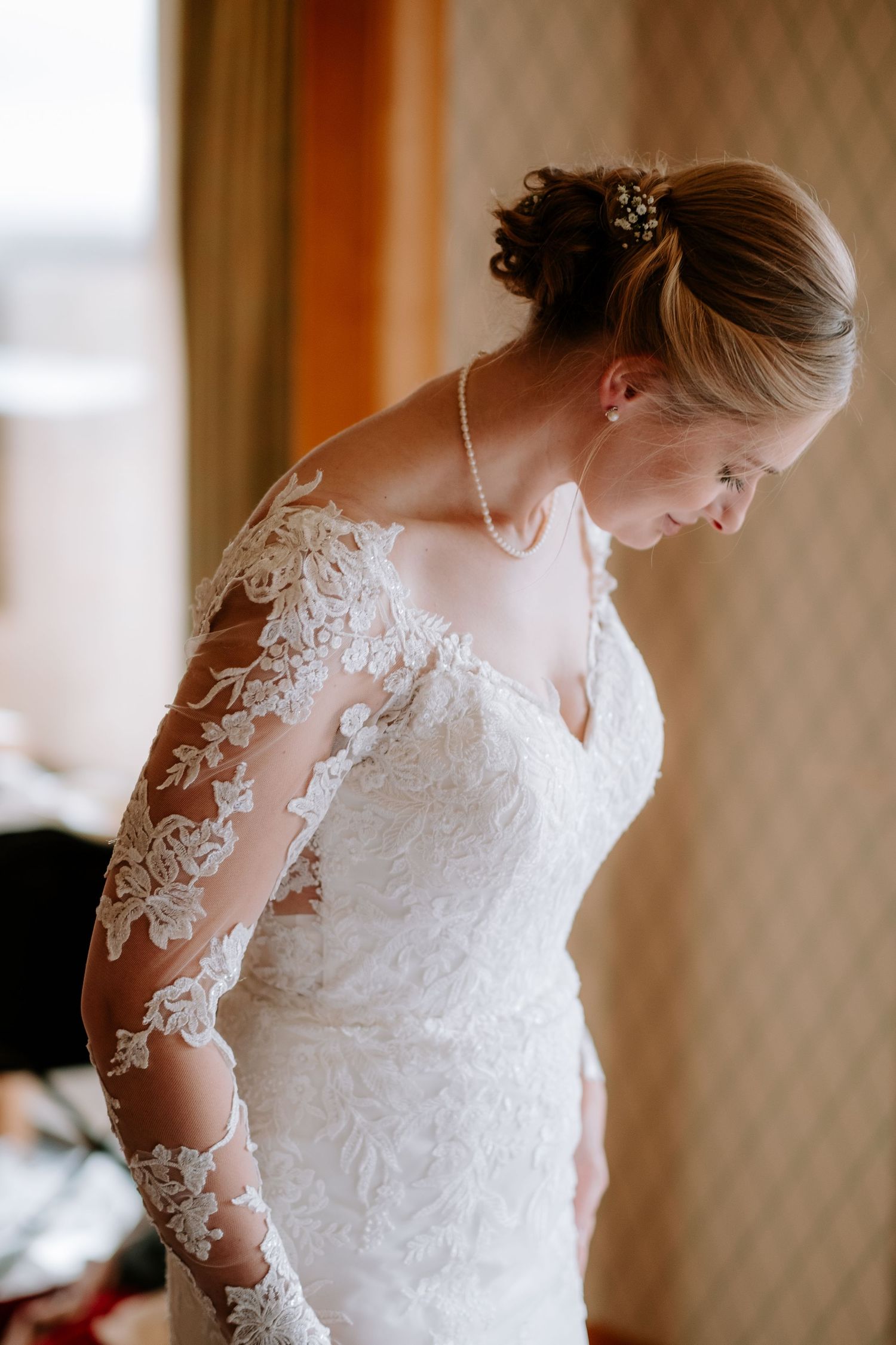 Close-up details of delicate lace wedding dress with sheer sleeves.