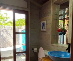 Modern bathroom with blue bowl sink, wood-paneled walls, and sliding glass door revealing outdoor pool area.