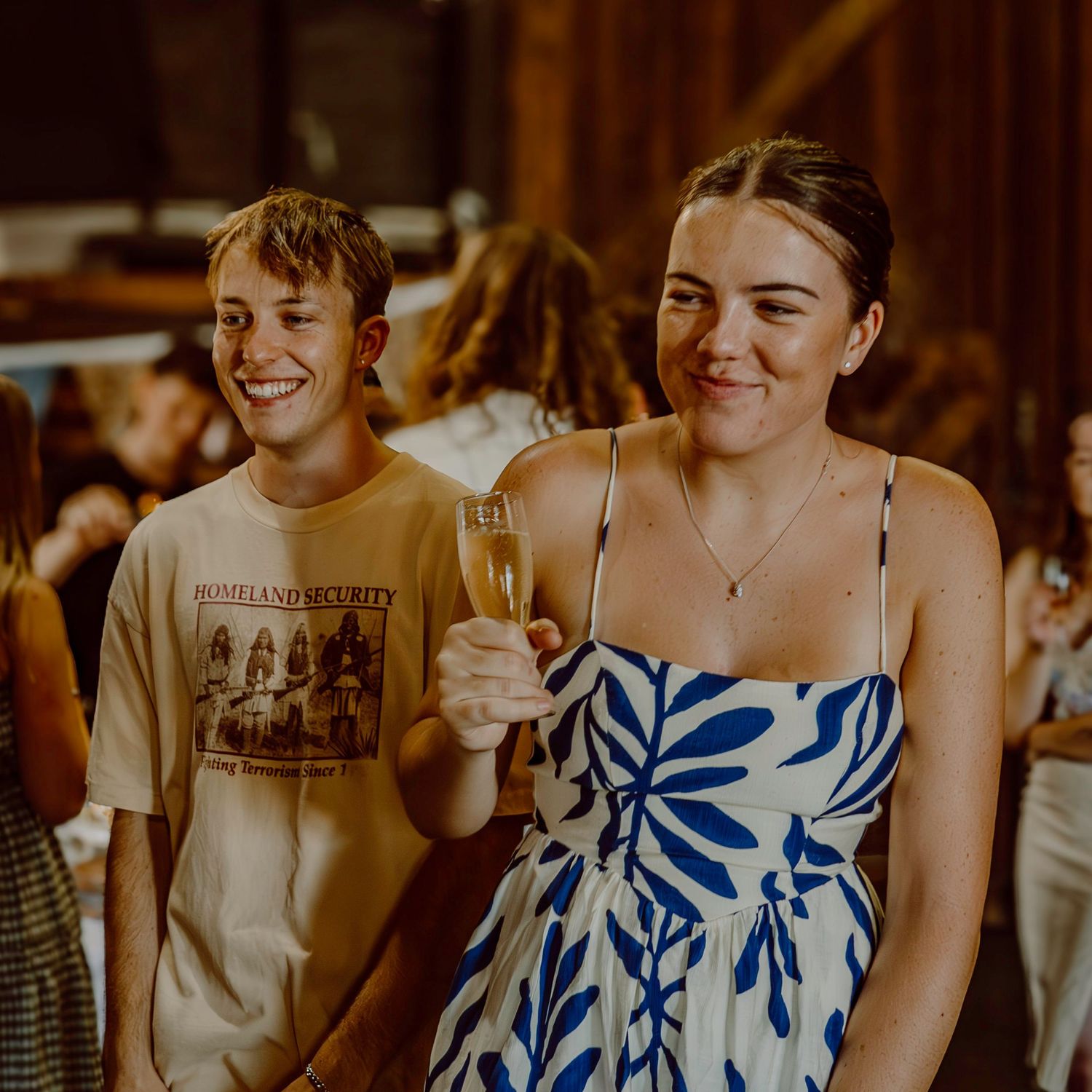 Two people share drinks and laughter at an indoor celebration.