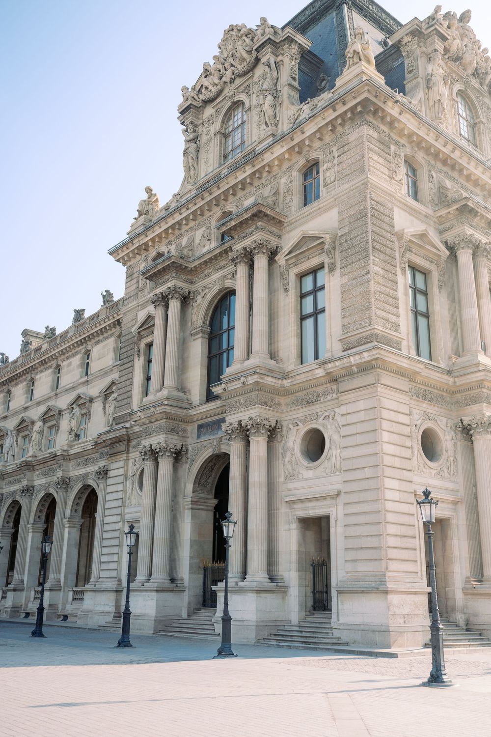 Ornate facade of the Louvre Museum in Paris, featuring classical French architecture with columns and decorative stonework.