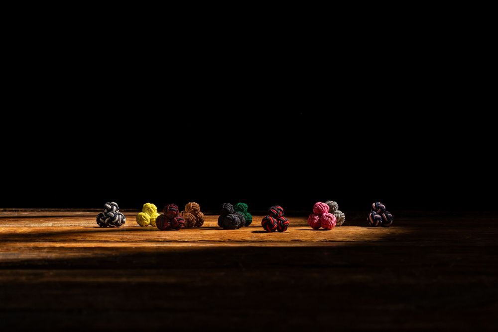 Colorful small figurines arranged in a row on a rustic wooden surface against a dark black background.