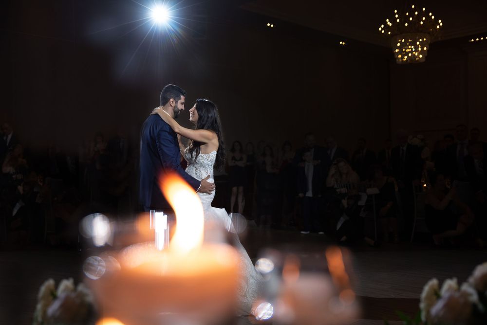 Bride and groom sharing an intimate first dance silhouette with candles in the foreground and guests watching.