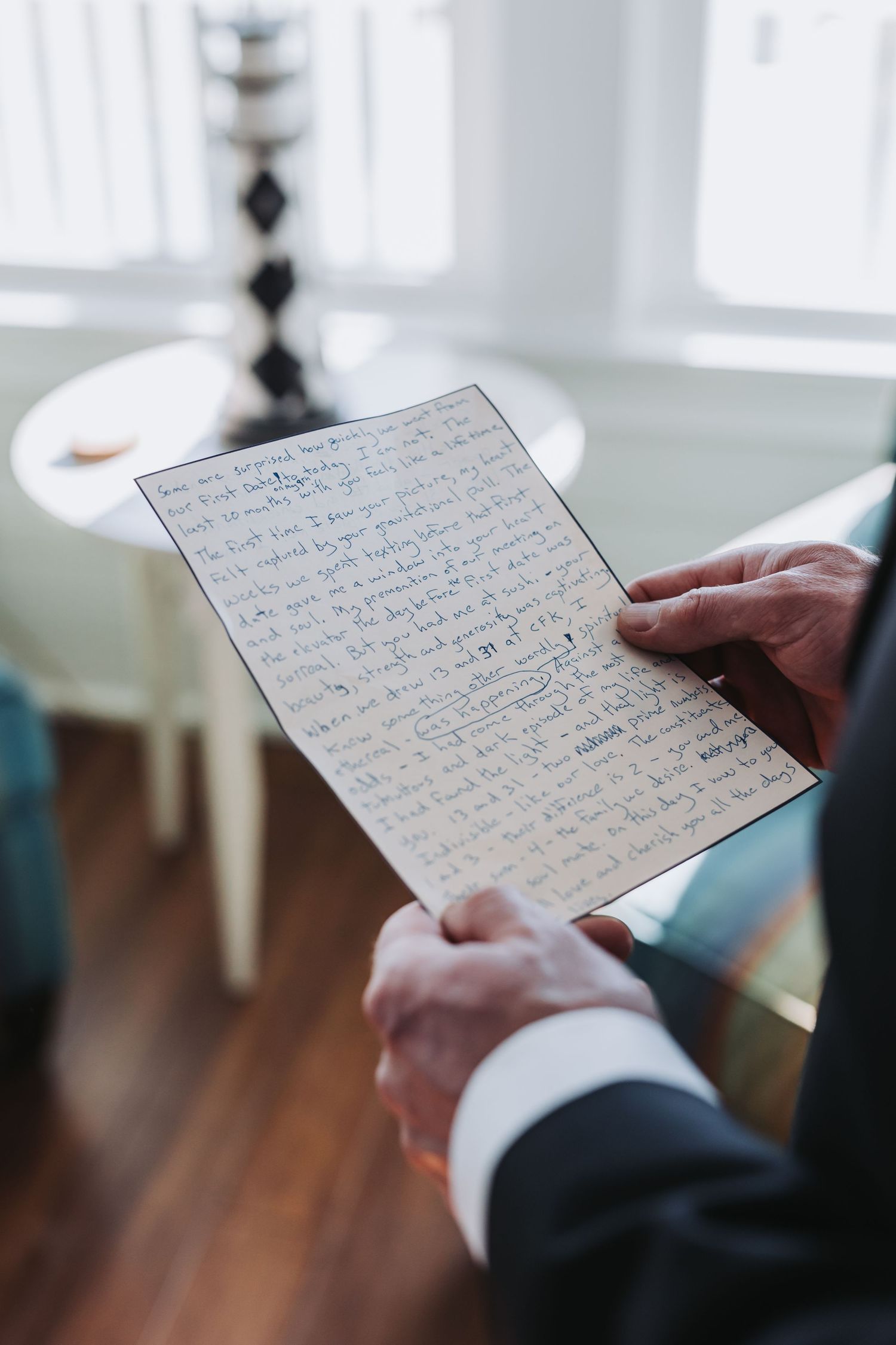 Close-up of groom's hands holding handwritten wedding vows on aged paper before the ceremony.