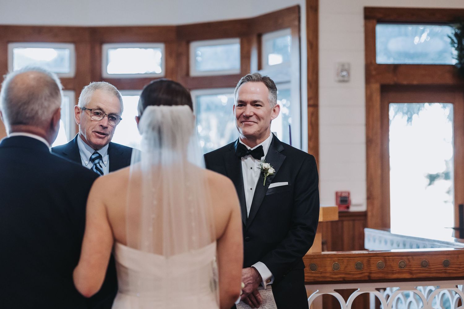 Groom smiling warmly at his bride during their wedding ceremony at an elegant indoor venue.