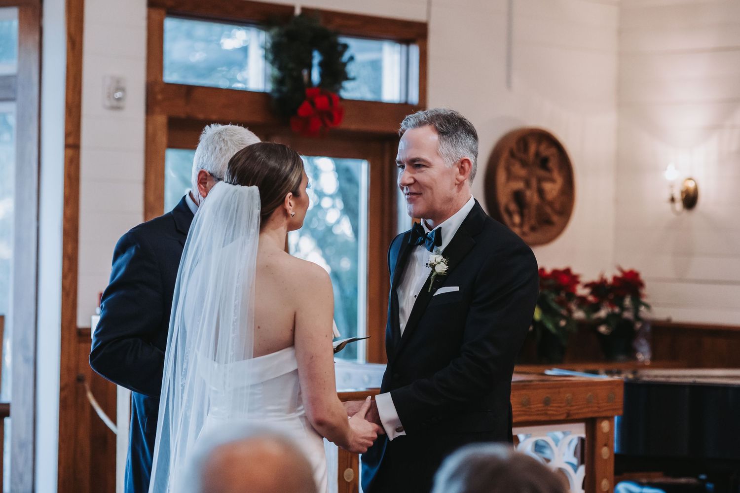 Groom smiles warmly at veiled bride during intimate church wedding ceremony exchange.