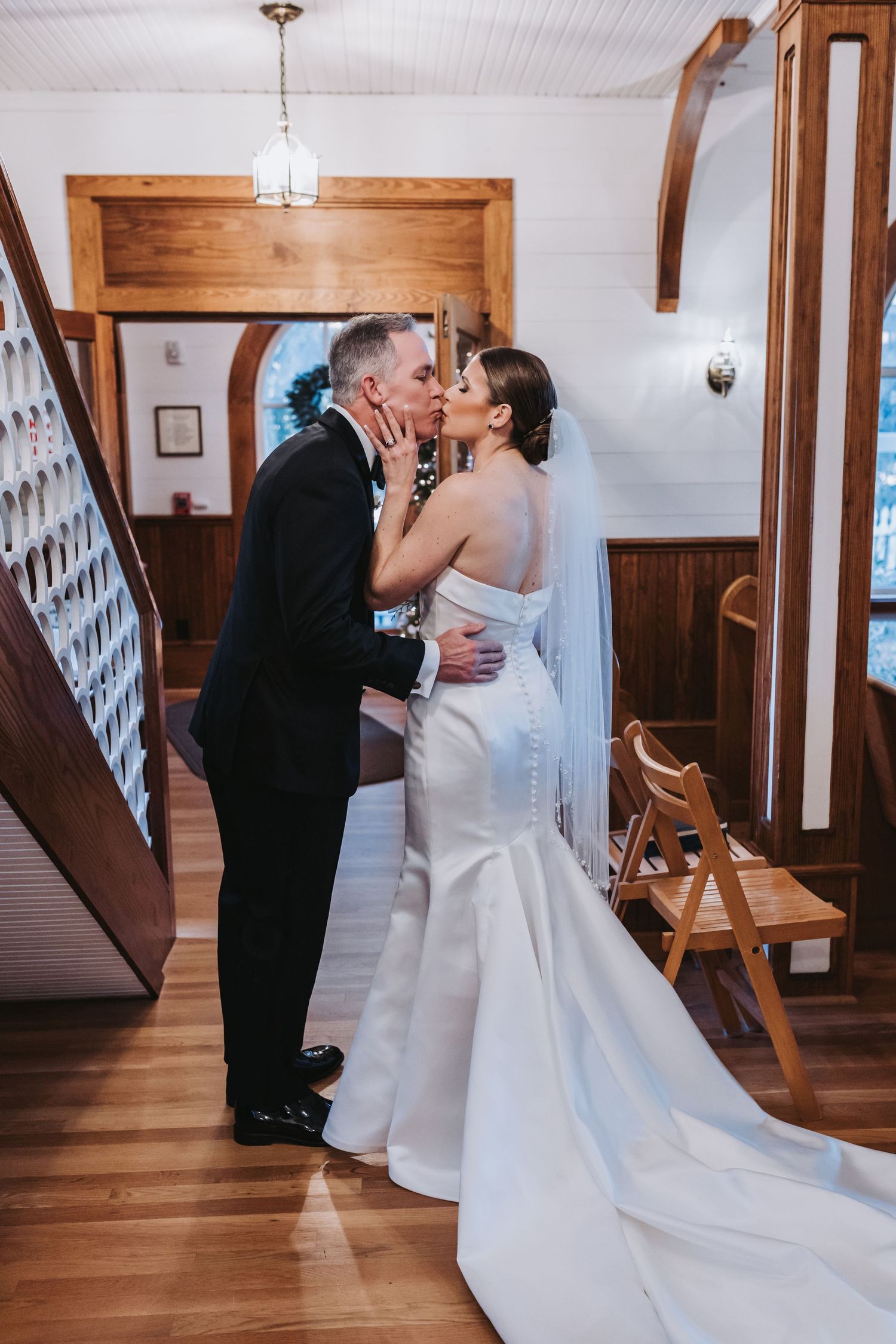 Newlyweds sharing their first kiss as a married couple inside a charming wooden chapel.