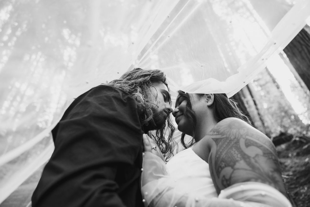 Black and white wedding photo of bride and groom sharing an intimate moment under a veil.