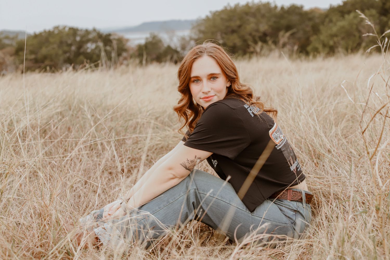 Red-haired high school senior seated in a dry grass field