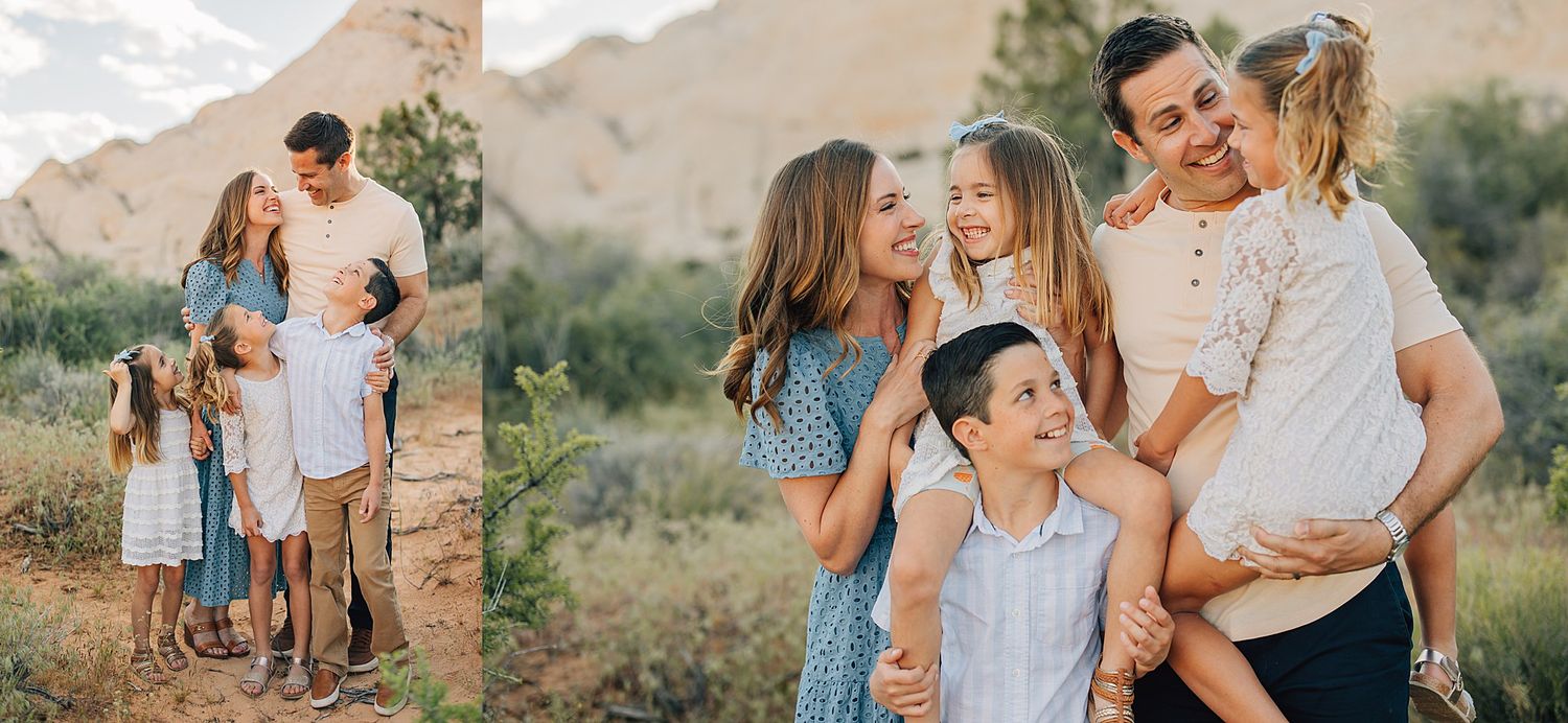 A joyful family of five laughs and cuddles together outdoors in a scenic desert landscape.