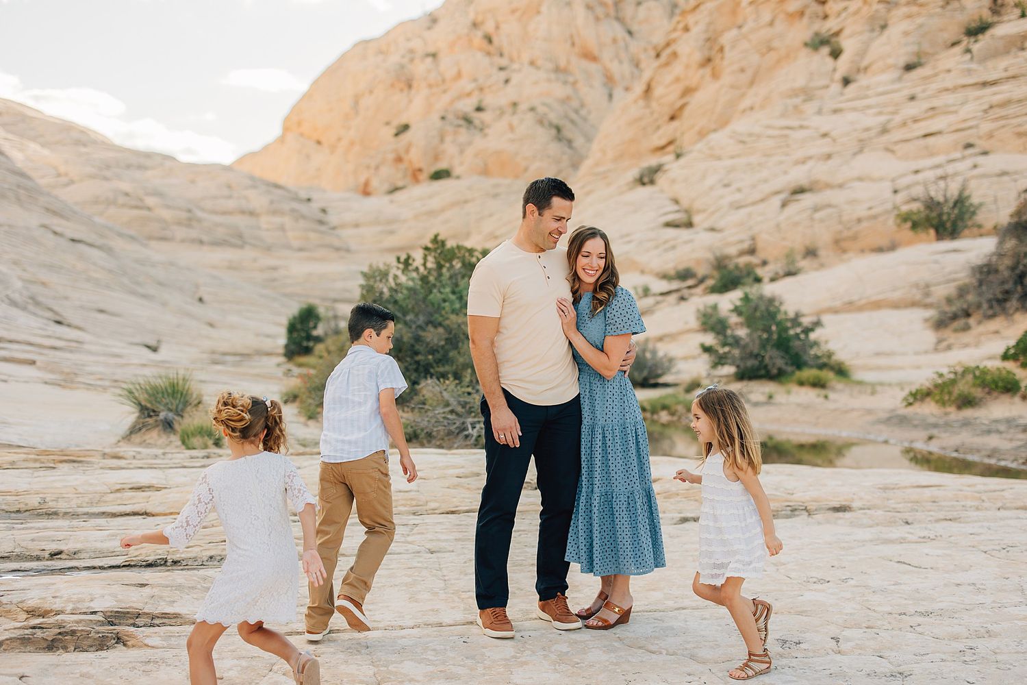 Family of five posing in a scenic desert landscape with sandy rock formations in warm natural light.