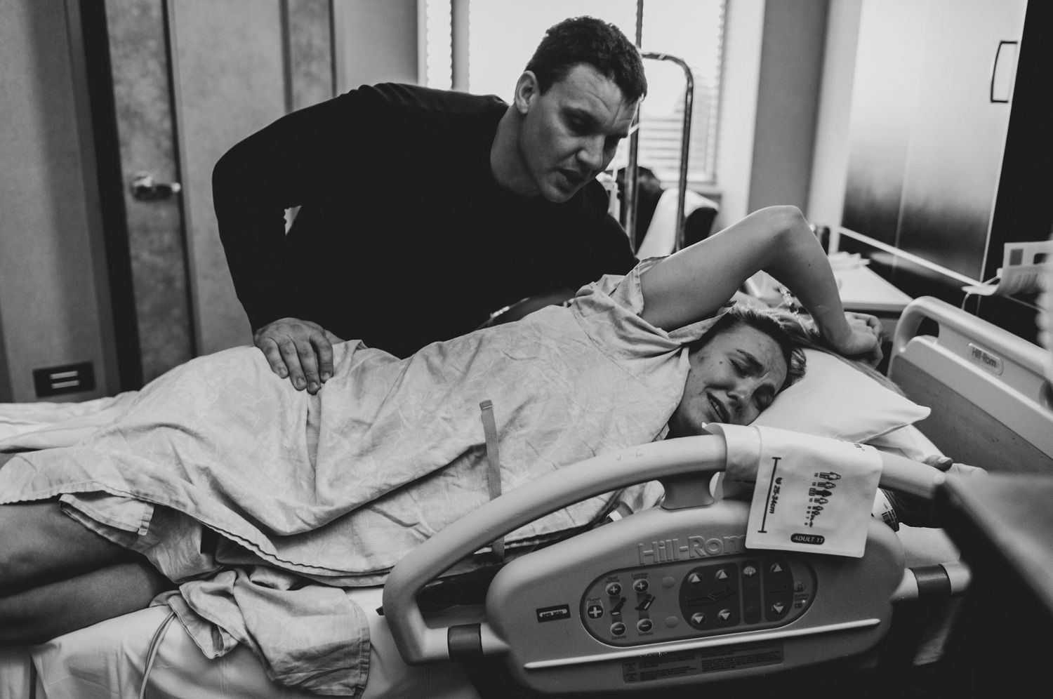 Black and white image showing supportive presence at hospital bedside.