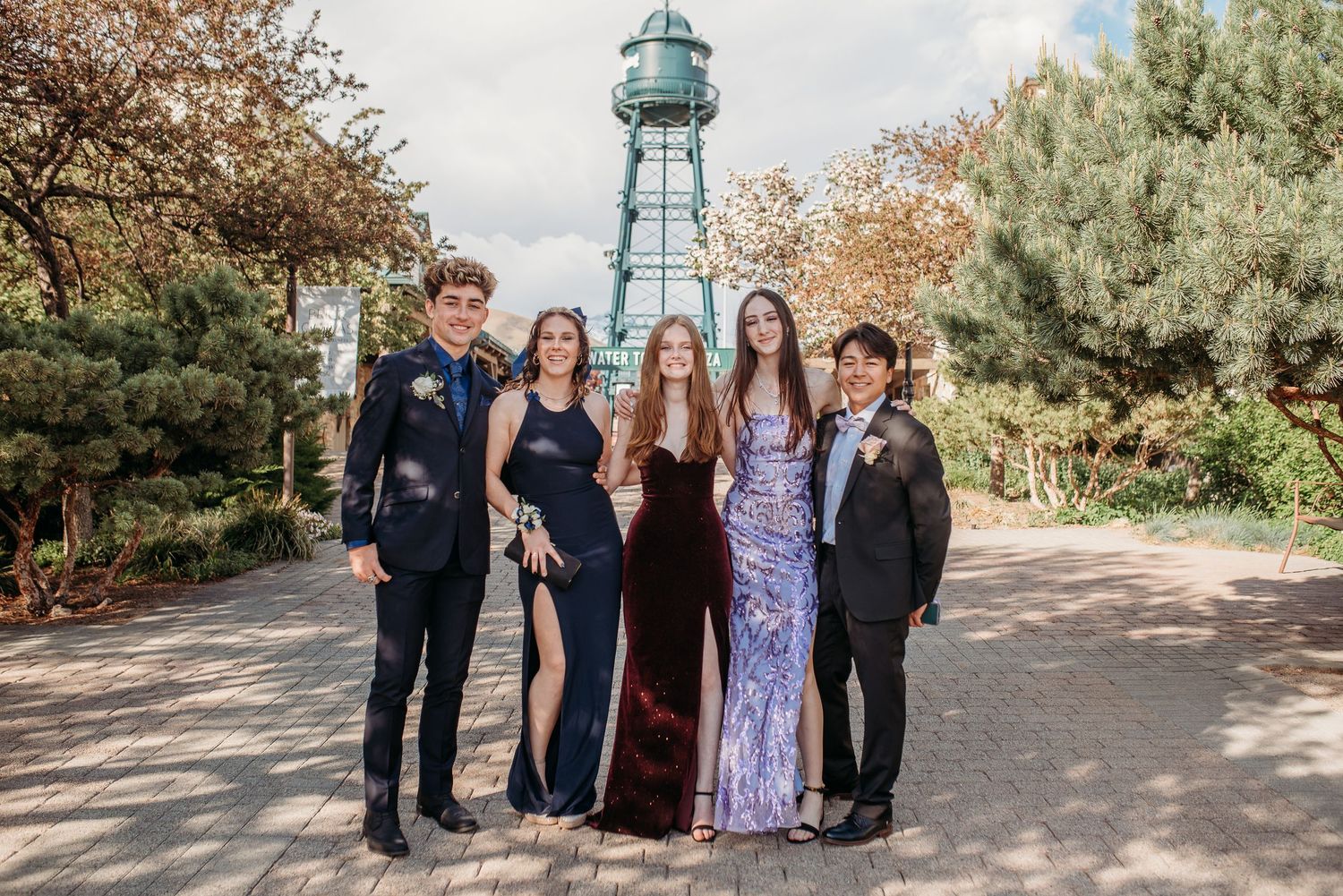 Formal group photo of people in evening wear posing in front of a lighthouse tower.