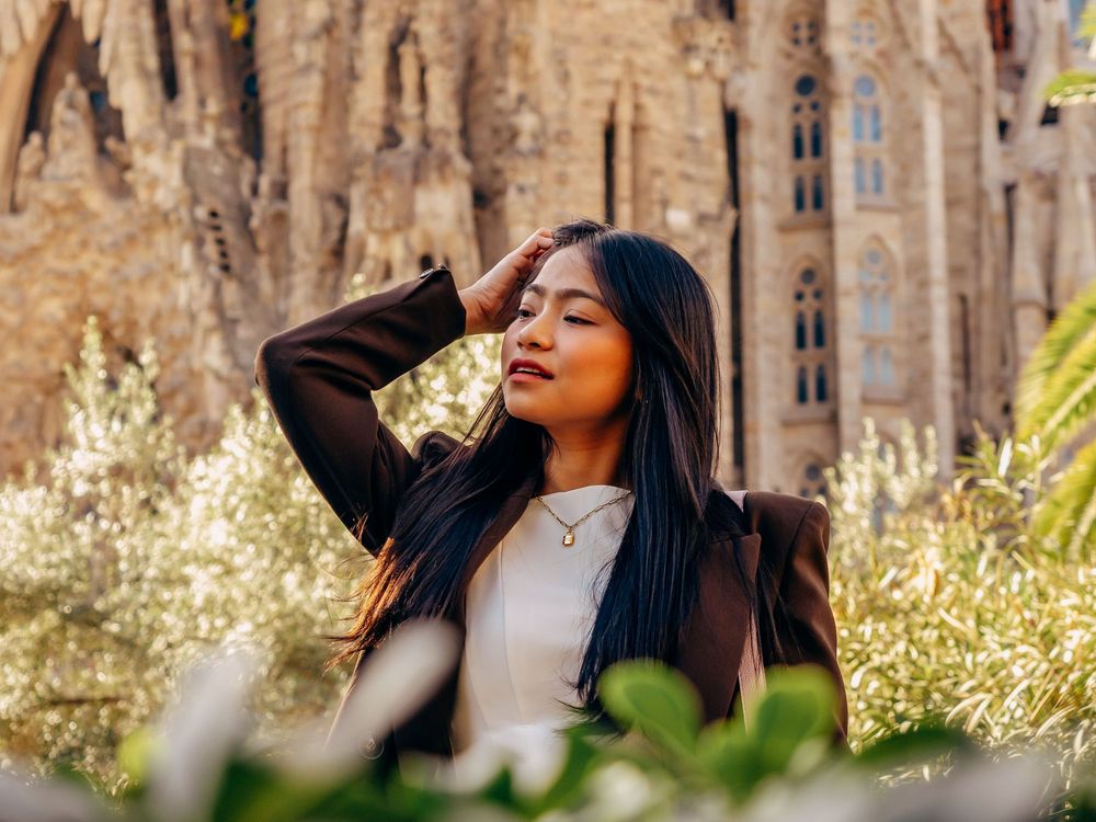 Young woman posing gracefully in front of Sagrada Familia basilica in Barcelona, Spain.