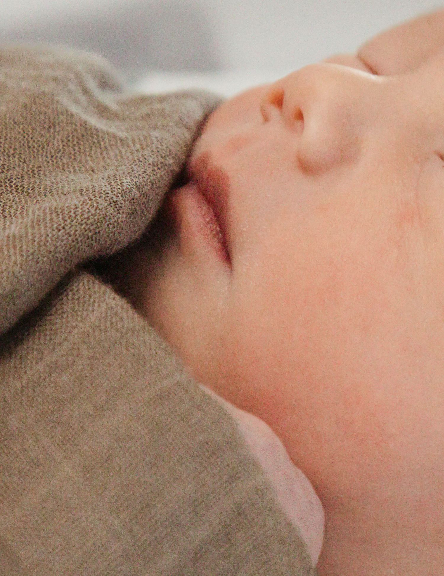 Close-up series of a sleeping baby swaddled in soft brown fabric.