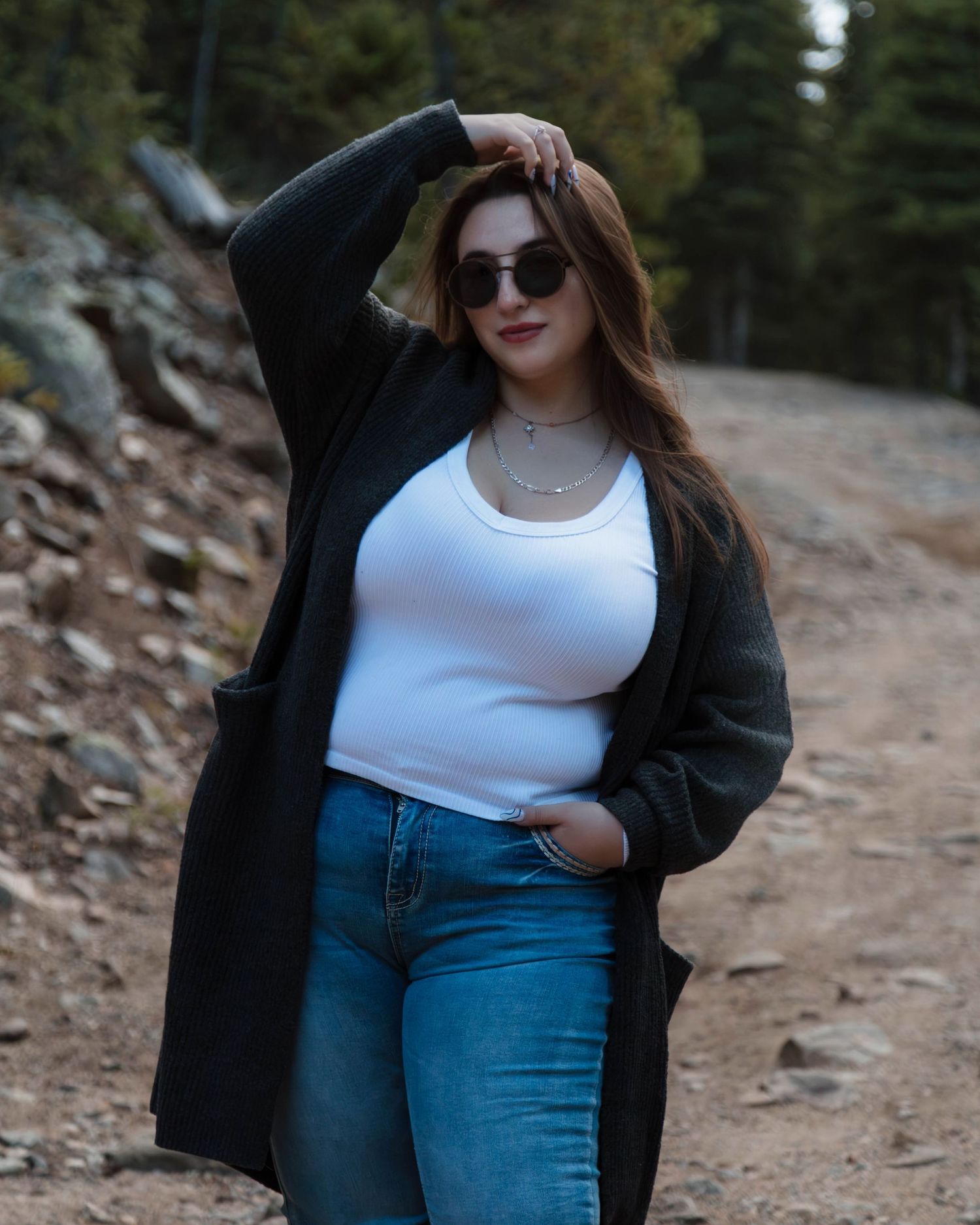 Casual outdoor fashion shoot on mountain trail with long black cardigan and jeans.