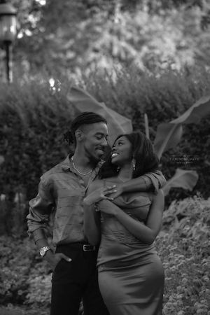 A romantic black and white photo of a couple laughing together outdoors in a garden setting.