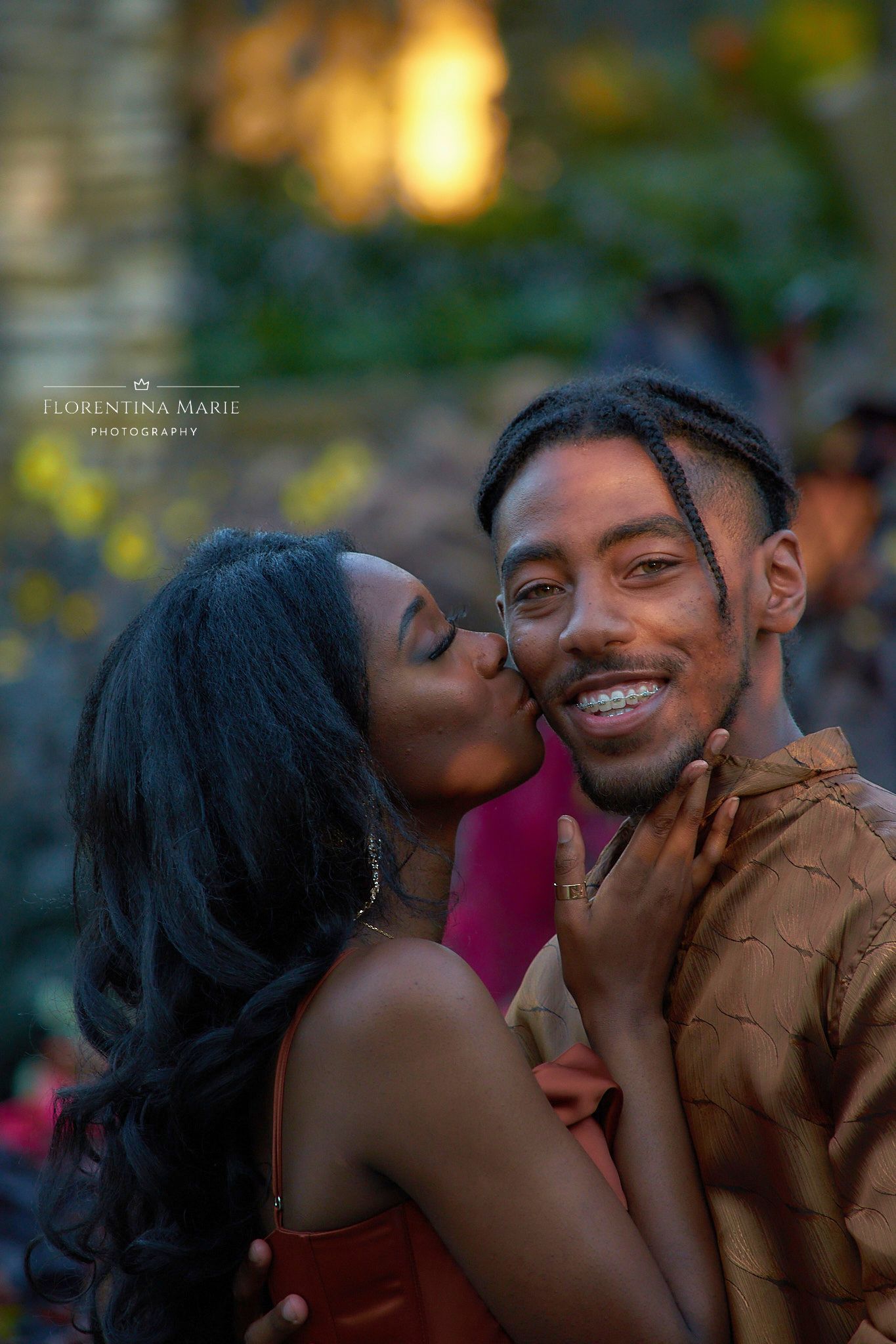 Young couple share an intimate moment outdoors at sunset with soft bokeh lighting in the background.