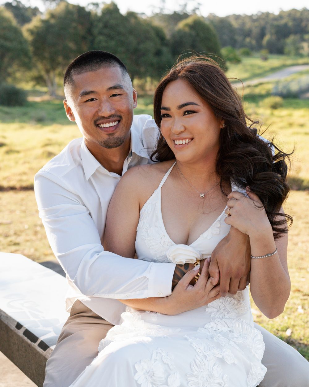 couple sitting on a bench, man hugging his wife and smiling towards the camera during a couples elopement photoshoot in sydney