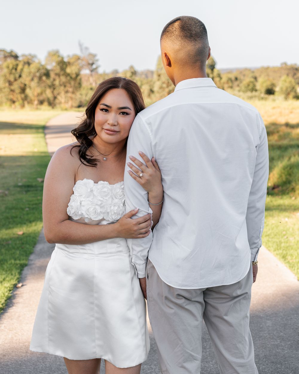 A couple in white and grey formal wear shares intimate moments during an outdoor photo session.