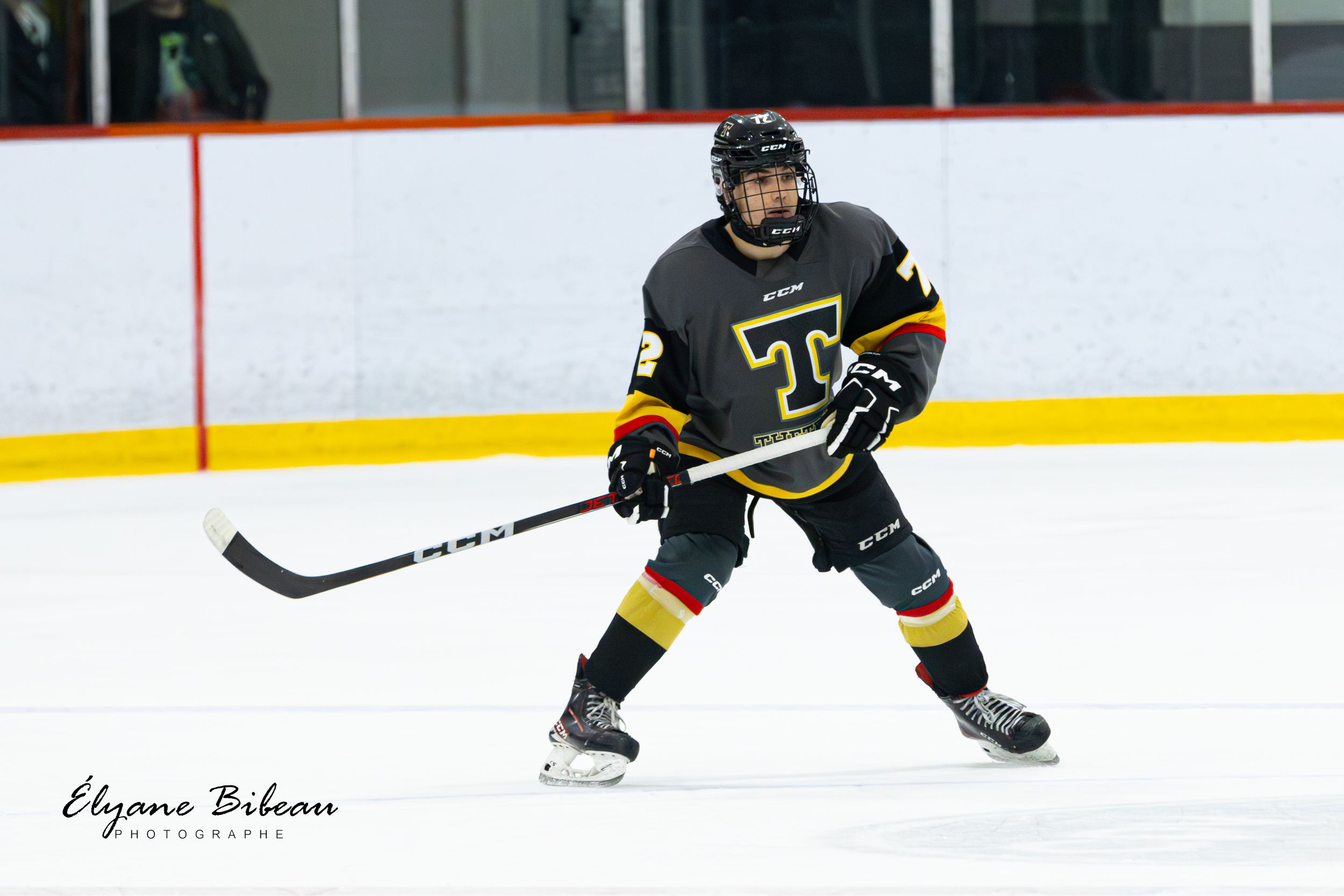 Player in black and gold hockey uniform maneuvers on ice during game action.