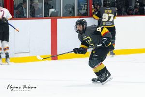 Hockey player in black and yellow uniform skates during intense game action.