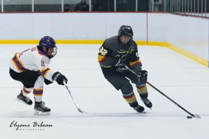 Two hockey players from opposing teams chase after the puck during competitive play.