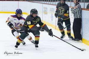 Players battle for puck control along the boards as referee watches nearby.