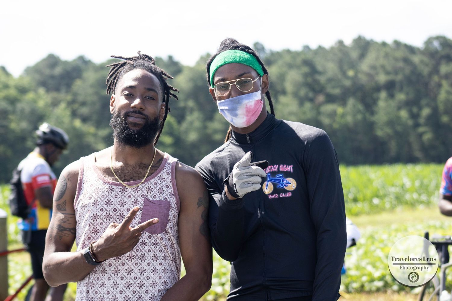 Two people wearing protective masks pose together in an outdoor field setting.