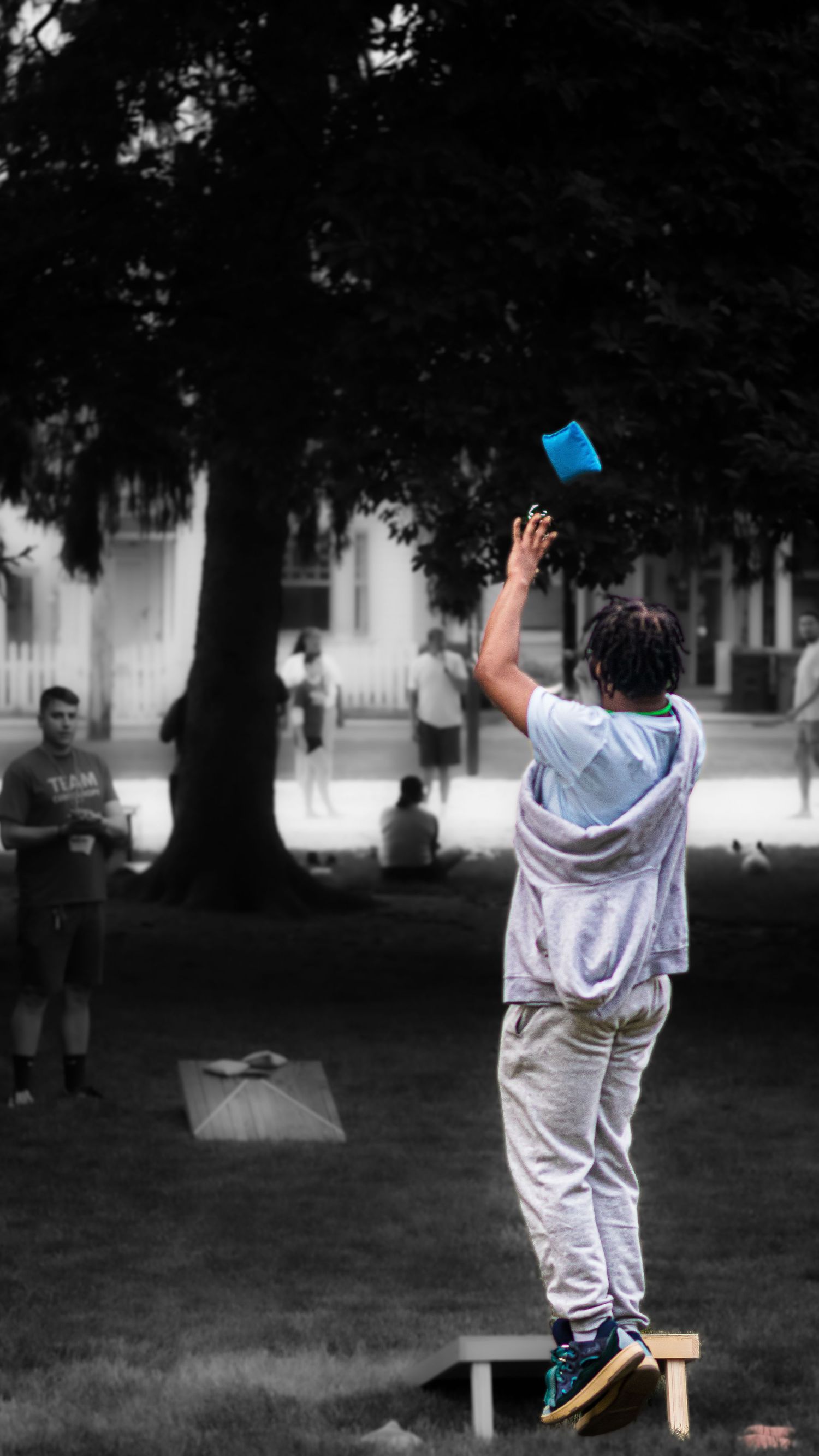 Person reaching for a blue object in selective color black and white photo.