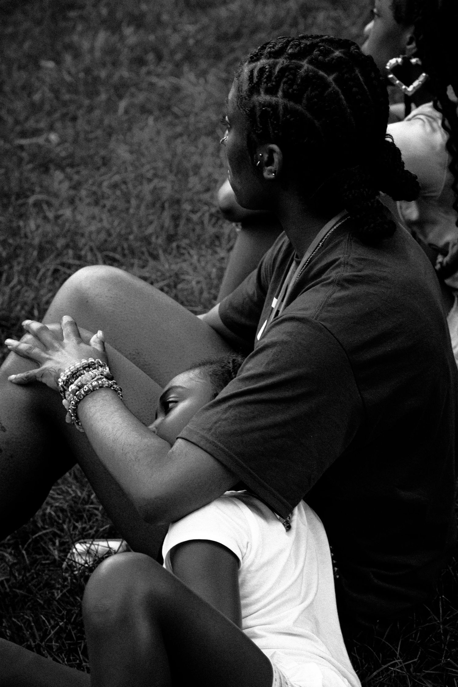 Side profile of someone with braided hair sitting outdoors in black and white.
