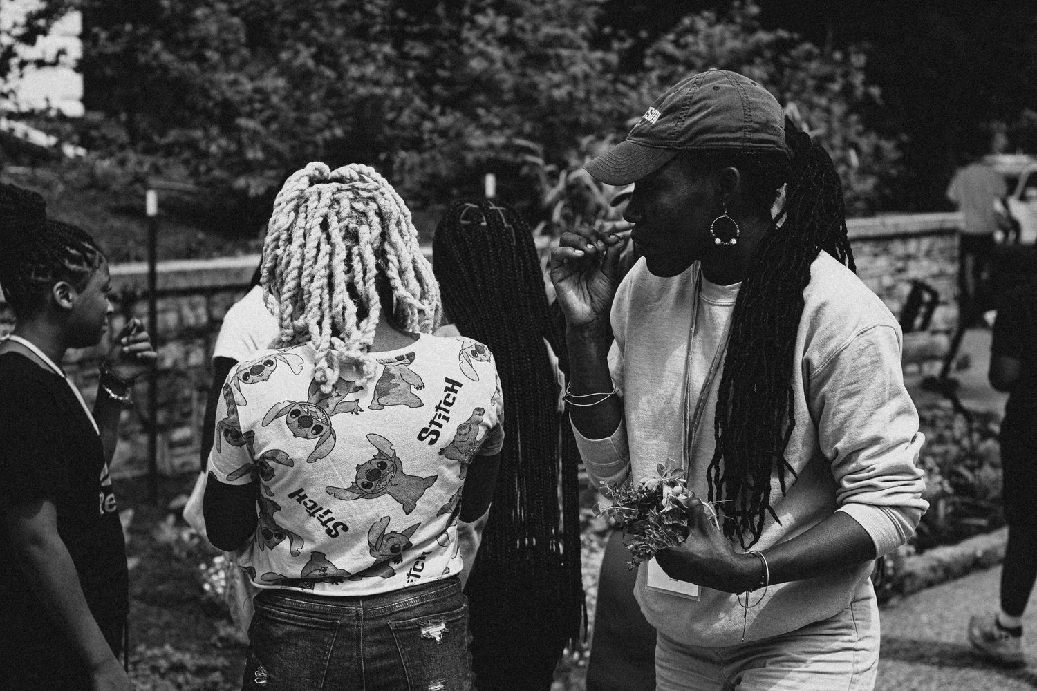 Black and white image showing people gathered outdoors in casual conversation.