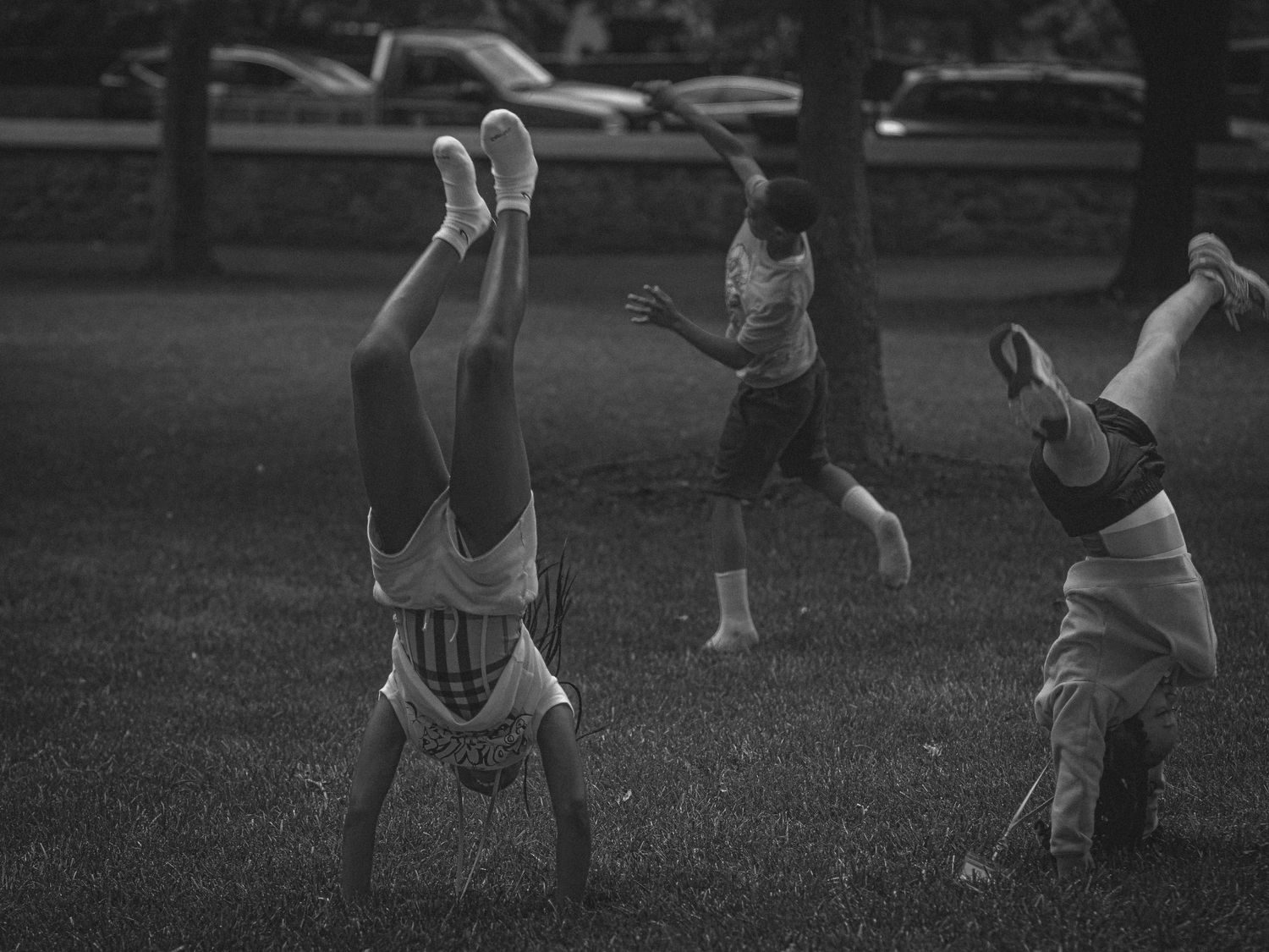 Children doing handstands and playing in a park on a summer day.
