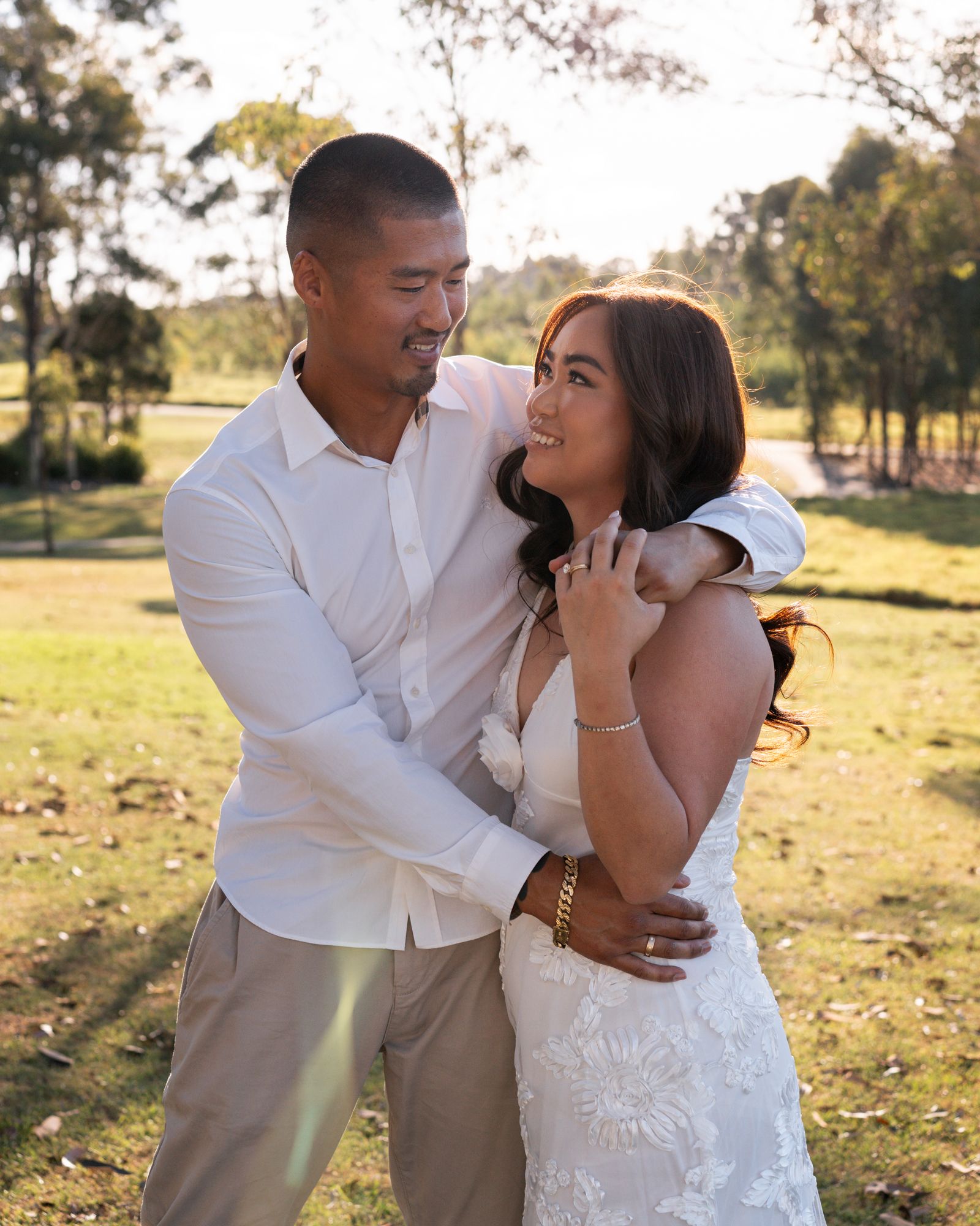 A playful couple in white shares an intimate moment in a scenic outdoor setting.